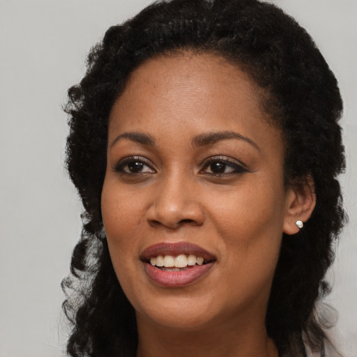 Joyful black young-adult female with long  brown hair and brown eyes
