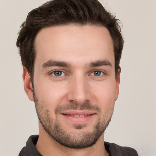 Joyful white young-adult male with short  brown hair and grey eyes