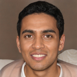 Joyful latino young-adult male with short  black hair and brown eyes