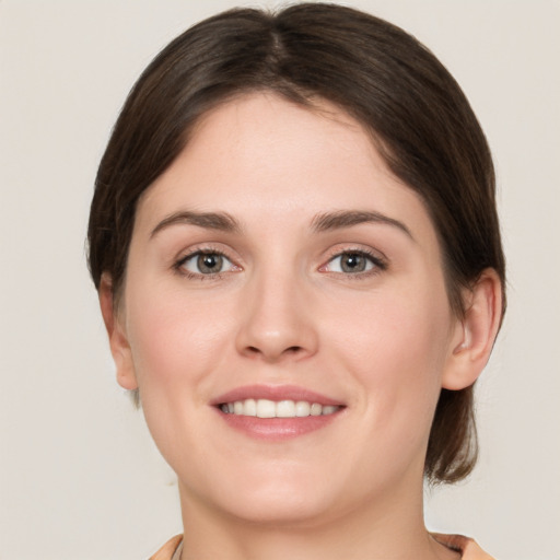 Joyful white young-adult female with medium  brown hair and grey eyes