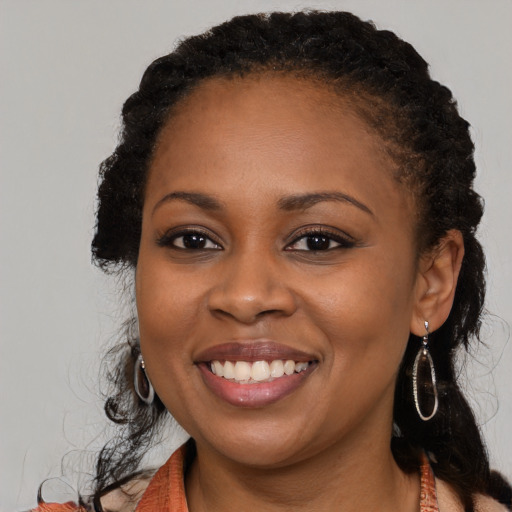 Joyful black young-adult female with long  black hair and brown eyes