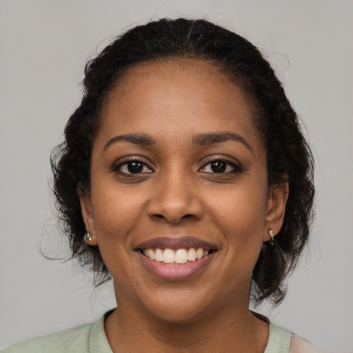 Joyful black young-adult female with long  brown hair and brown eyes