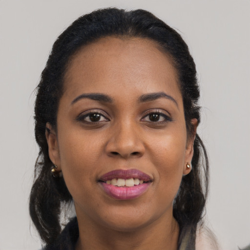Joyful black young-adult female with long  black hair and brown eyes
