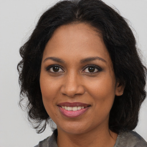 Joyful black young-adult female with long  brown hair and brown eyes