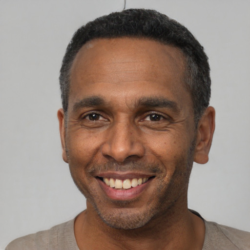 Joyful black adult male with short  black hair and brown eyes