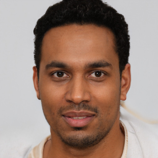 Joyful black young-adult male with short  black hair and brown eyes