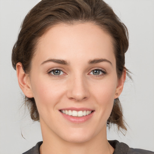 Joyful white young-adult female with medium  brown hair and grey eyes