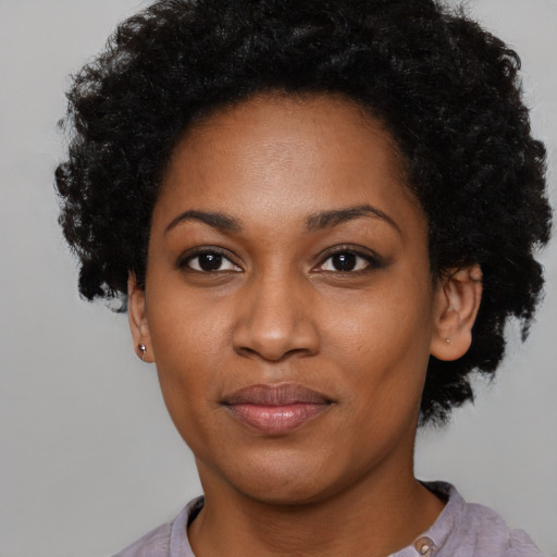 Joyful black young-adult female with short  black hair and brown eyes