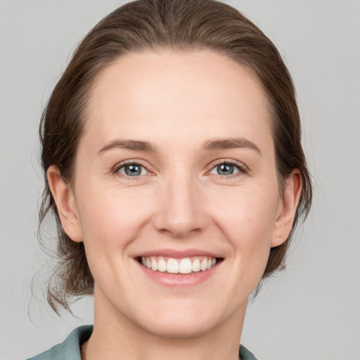 Joyful white young-adult female with medium  brown hair and grey eyes