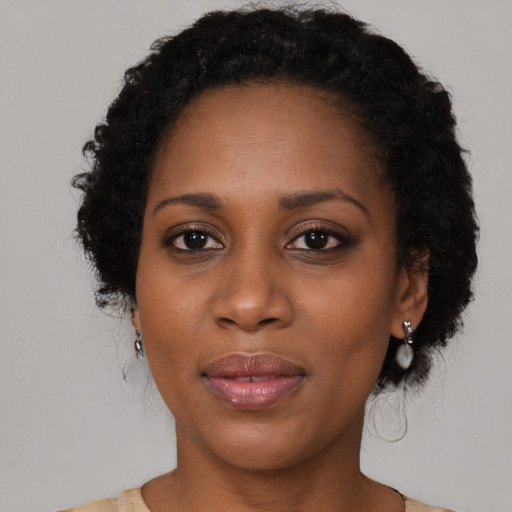 Joyful black young-adult female with long  brown hair and brown eyes