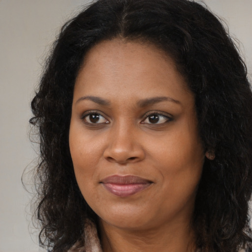 Joyful black young-adult female with long  brown hair and brown eyes