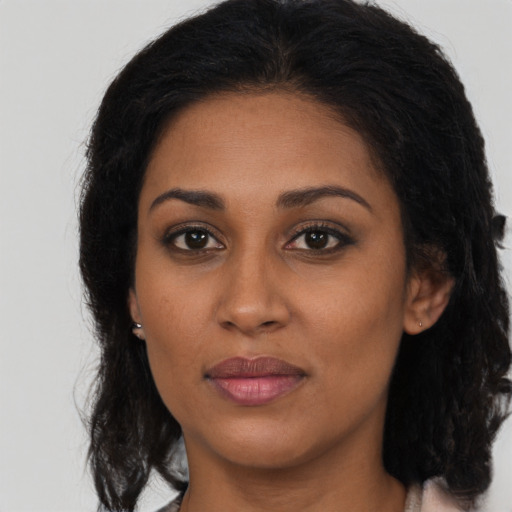 Joyful black young-adult female with long  brown hair and brown eyes