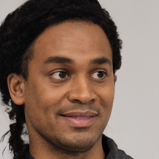 Joyful black young-adult male with short  brown hair and brown eyes