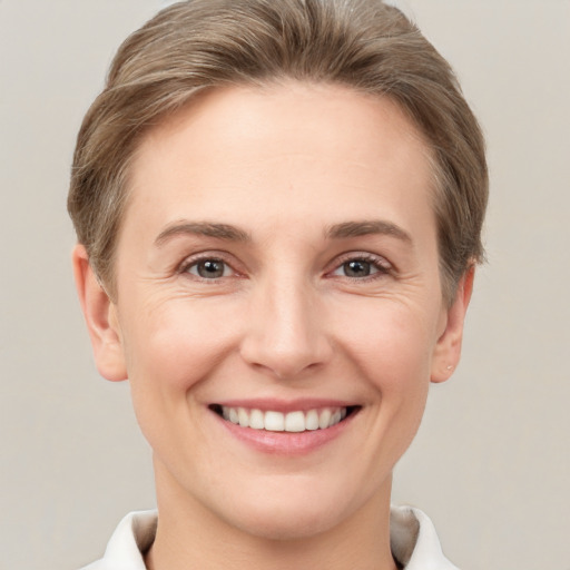 Joyful white young-adult female with short  brown hair and grey eyes