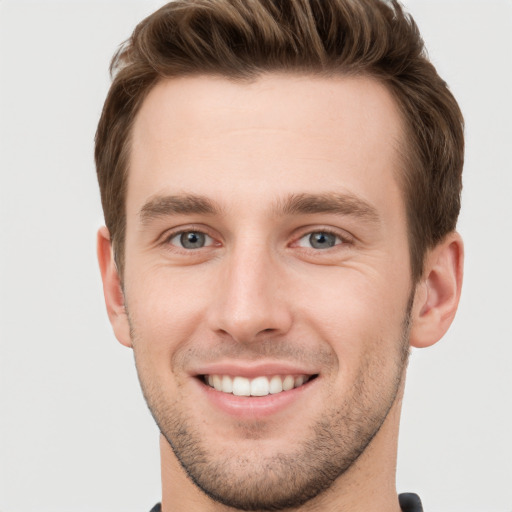 Joyful white young-adult male with short  brown hair and grey eyes