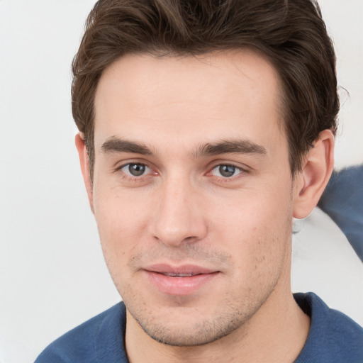 Joyful white young-adult male with short  brown hair and grey eyes