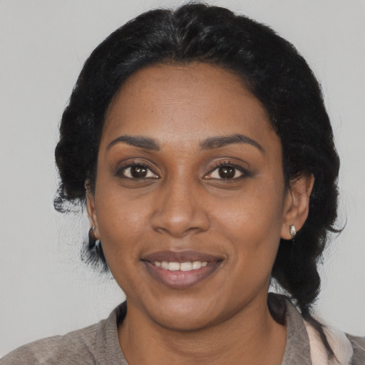 Joyful black young-adult female with long  black hair and brown eyes