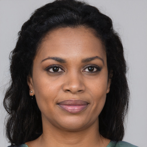 Joyful black young-adult female with long  brown hair and brown eyes