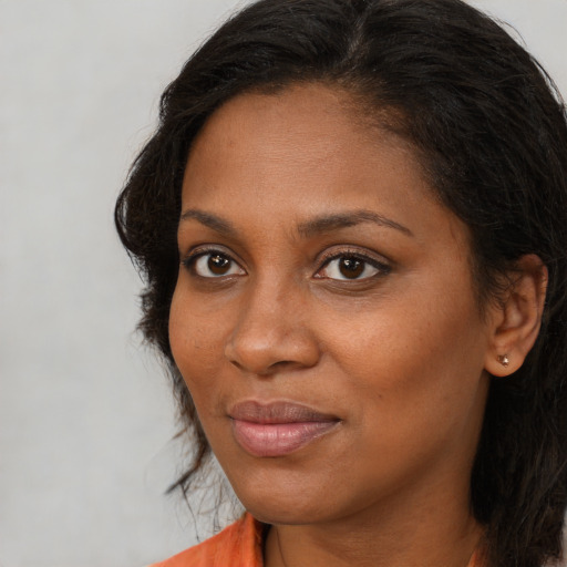 Joyful black young-adult female with long  brown hair and brown eyes