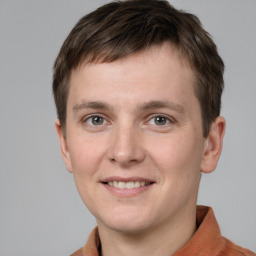 Joyful white young-adult male with short  brown hair and grey eyes