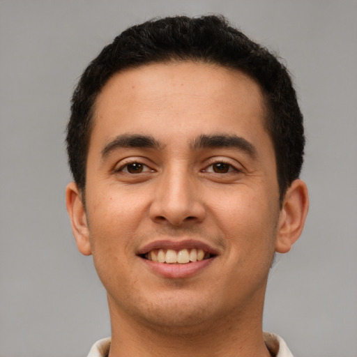 Joyful latino young-adult male with short  brown hair and brown eyes