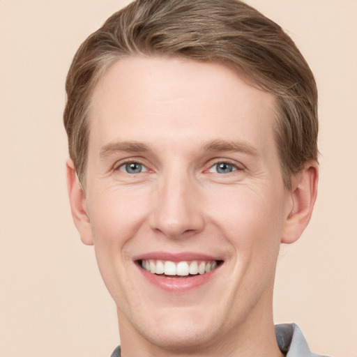 Joyful white young-adult male with short  brown hair and grey eyes