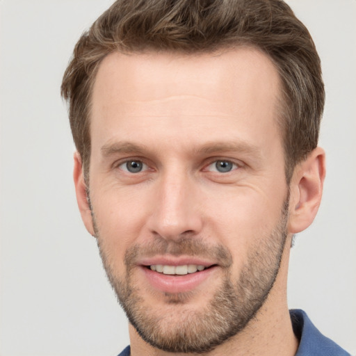 Joyful white young-adult male with short  brown hair and grey eyes