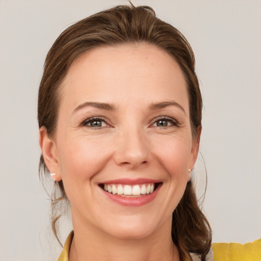 Joyful white young-adult female with medium  brown hair and grey eyes