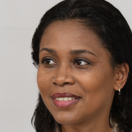 Joyful black adult female with long  brown hair and brown eyes