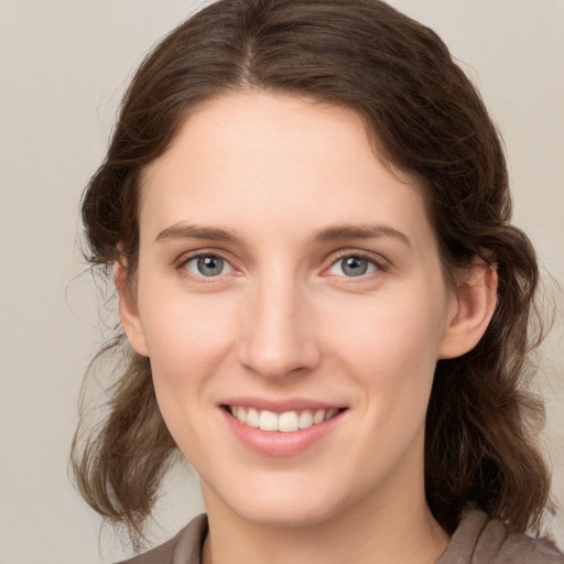 Joyful white young-adult female with medium  brown hair and grey eyes