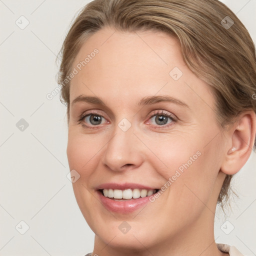 Joyful white young-adult female with medium  brown hair and grey eyes