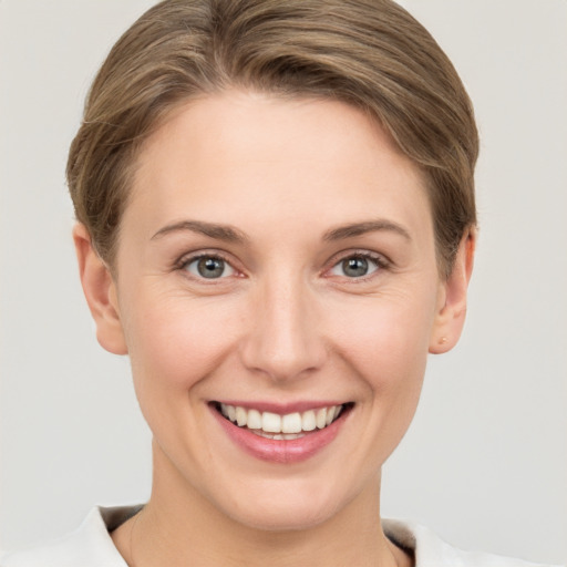 Joyful white young-adult female with short  brown hair and grey eyes