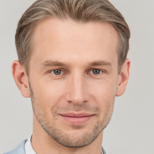 Joyful white young-adult male with short  brown hair and grey eyes