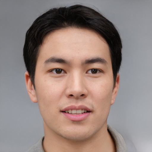 Joyful asian young-adult male with short  brown hair and brown eyes