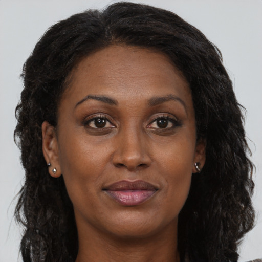 Joyful black adult female with long  brown hair and brown eyes