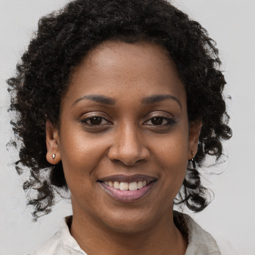 Joyful black young-adult female with long  brown hair and brown eyes