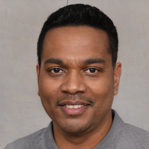 Joyful black young-adult male with short  black hair and brown eyes