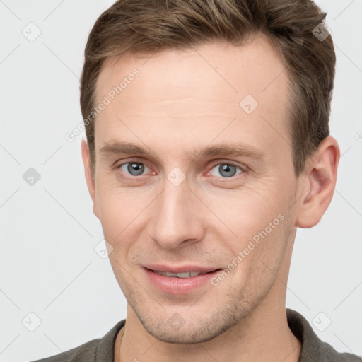 Joyful white young-adult male with short  brown hair and grey eyes