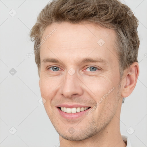 Joyful white adult male with short  brown hair and grey eyes