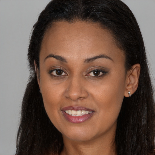 Joyful black young-adult female with long  brown hair and brown eyes