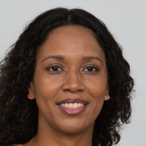 Joyful black adult female with long  brown hair and brown eyes