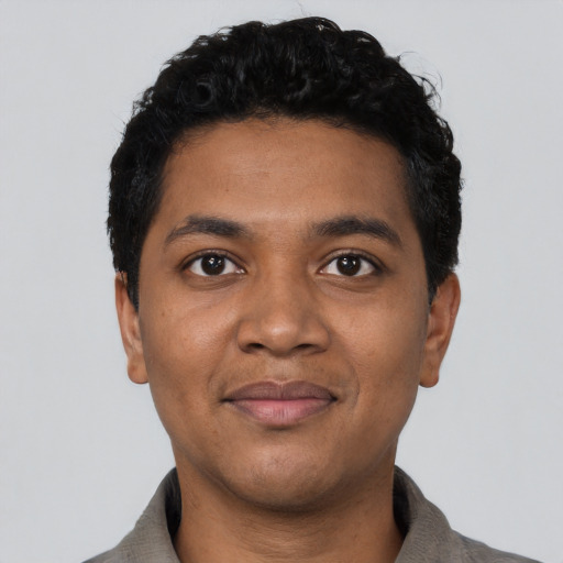 Joyful black young-adult male with short  black hair and brown eyes