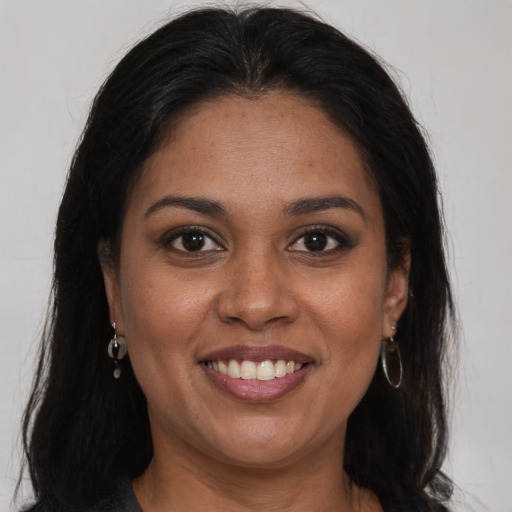 Joyful black young-adult female with long  brown hair and brown eyes