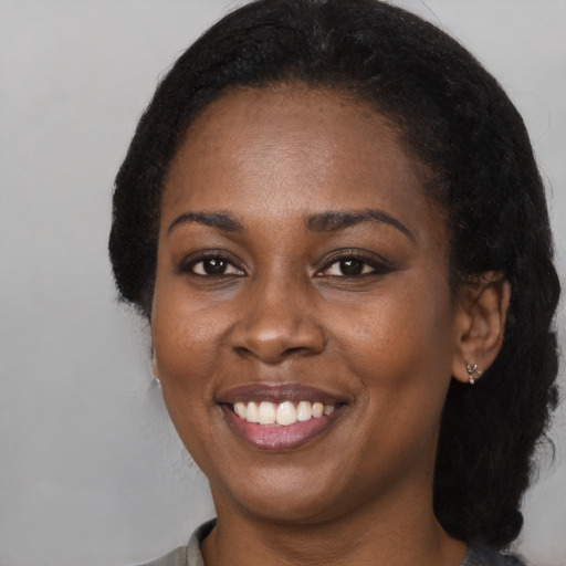 Joyful black young-adult female with long  black hair and brown eyes