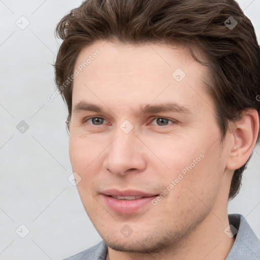 Joyful white young-adult male with short  brown hair and grey eyes