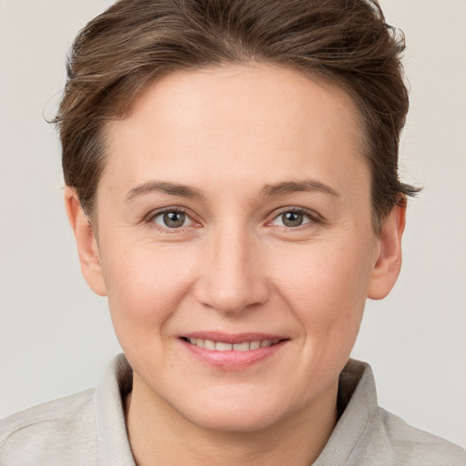 Joyful white young-adult female with short  brown hair and grey eyes