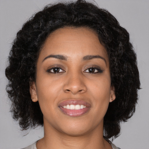 Joyful black young-adult female with long  black hair and brown eyes