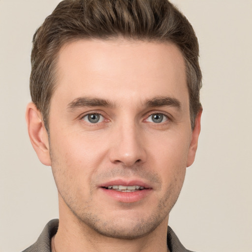 Joyful white young-adult male with short  brown hair and grey eyes