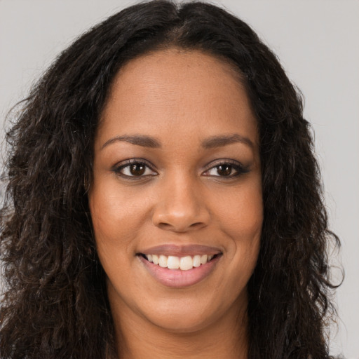 Joyful black young-adult female with long  brown hair and brown eyes