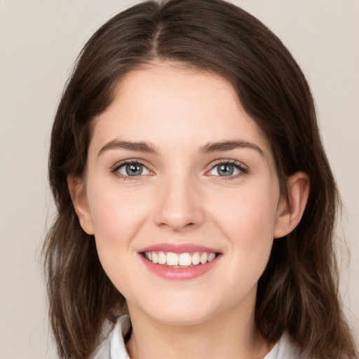 Joyful white young-adult female with medium  brown hair and grey eyes